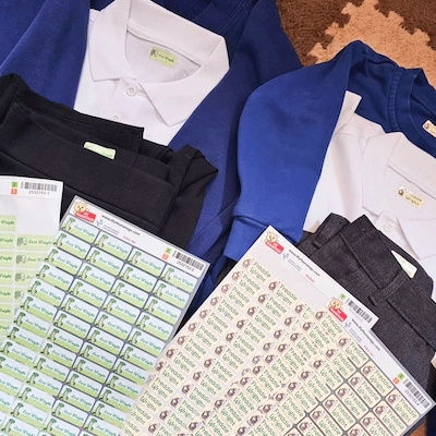 Tenues d'école bleues et blanches à côté de planches d'étiquettes thermocollantes vertes